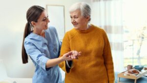 This picture depicts Alzheimer's and Medicare. A nurse holds the hand of a senior woman.